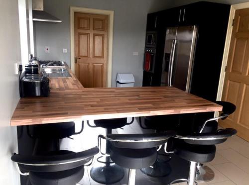 a kitchen with a wooden counter with stools around it at Leghowney House in Donegal
