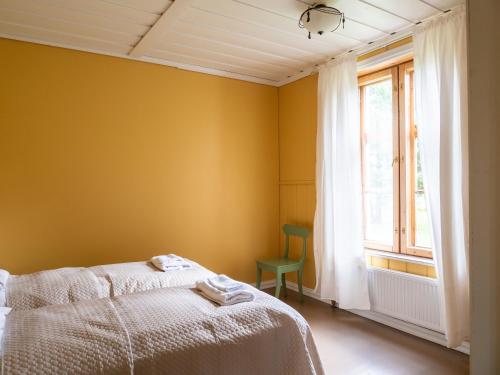 a bedroom with yellow walls and a bed and a window at Haapala Brewery restaurant and accommodation in Vuokatti
