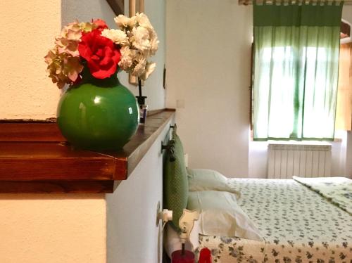 a green vase with flowers on a counter next to a bed at Il Casolare in Penna