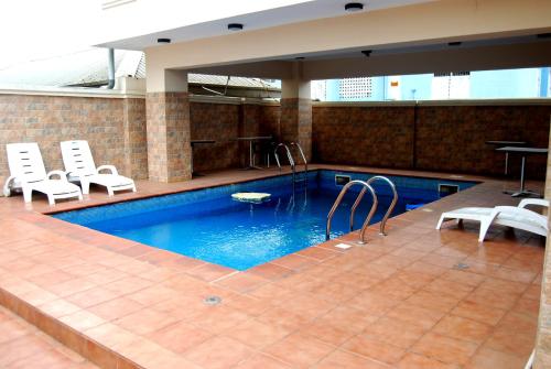 a large swimming pool with chairs and a table and a pool at Grand Inn & Suites in Ijebu Ode
