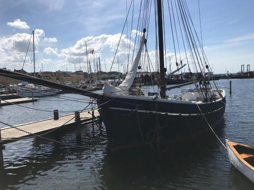 a black boat docked at a dock in the water at Villa Wiegand - a room with a view in Holbæk