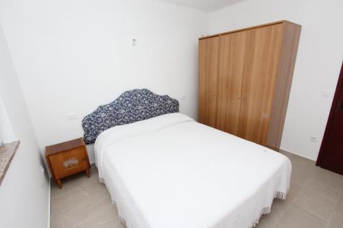 a bedroom with a white bed and a wooden cabinet at Apartment Mihaela in Rovinj