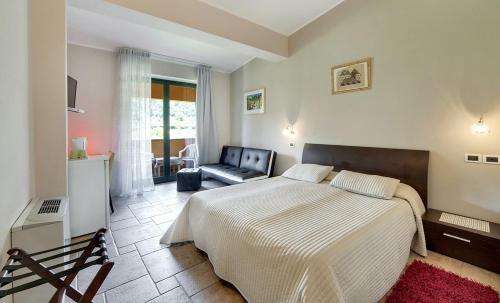 1 dormitorio con 1 cama, 1 silla y 1 sofá en Casale Romano Resort e Relais, en Motta Camastra