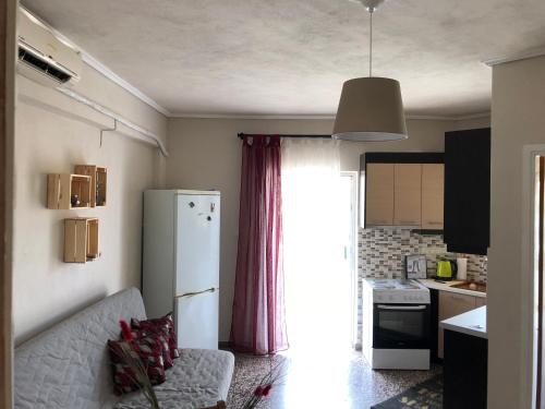 a kitchen with a couch and a white refrigerator at Summer House close to the sea @ Almiri, Corinth in Kórinthos