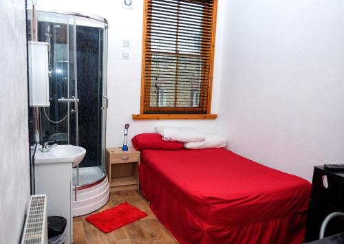 ein kleines Schlafzimmer mit einem roten Bett und einem Waschbecken in der Unterkunft Shrimp Terrace in Sheerness