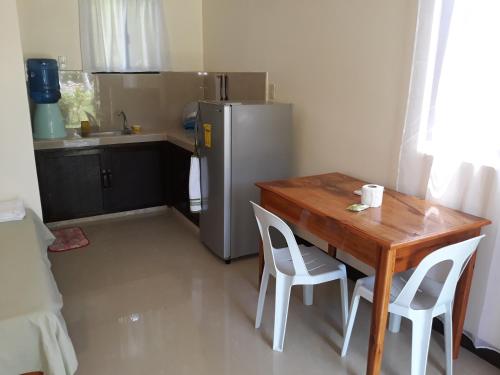 a kitchen with a wooden table and a refrigerator at Gardenview Homestay Siargao in General Luna