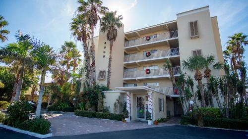 a building with palm trees in front of it at Beach and sunset view from your balcony in Longboat Key