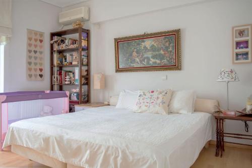 a bedroom with a white bed and a painting on the wall at Luxurious apt in the Athenian Riviera in Athens