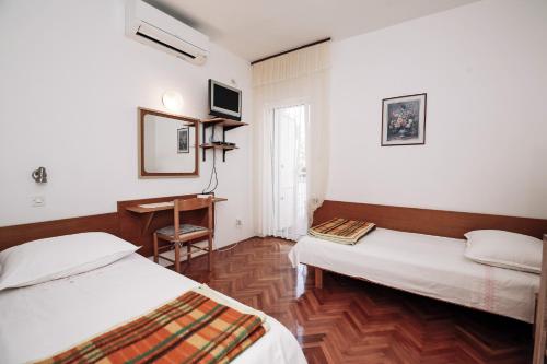 a room with two beds and a desk in it at Apartments & Rooms Peranic in Novalja