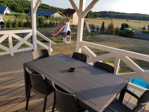 a table and chairs on a deck with a playground at Domek Aneczka Dębina in Dębina