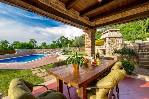 patio con tavolo in legno e piscina di Villa Lea & Tea a Tinjan