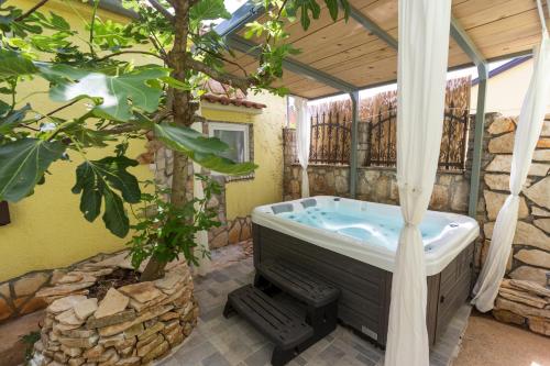 a bathroom with a hot tub and a tree at Green house, WI-FI, FREE PARKING, GARDEN, HOT TUBE in Peroj