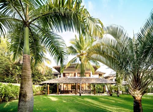 a house with two palm trees in front of it at Campo Bahia Hotel Villas Spa in Santo André
