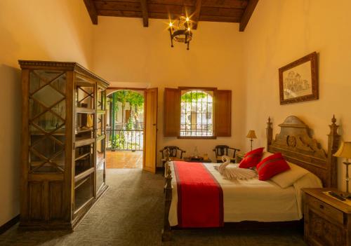アンティグア・グアテマラにあるHotel Posada de Don Rodrigo Antiguaのベッドルーム1室(大型ベッド1台、赤い枕付)