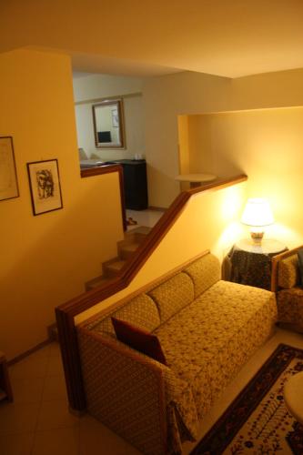 a living room with a couch and stairs with a lamp at Hotel Elimo in Erice