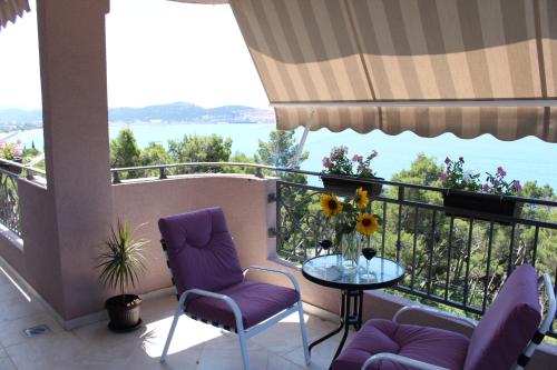 balcón con sillas moradas y mesa de cristal en Vila POGLED, en Bar