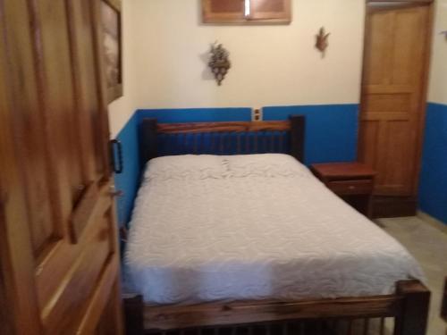 a small bed in a room with a blue wall at Hotel Atenas Jericó in Jericó