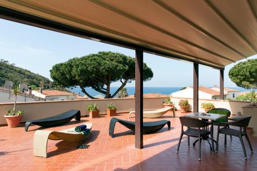 un patio con sillas y mesas y vistas al océano en Hotel Corallo en Pomonte