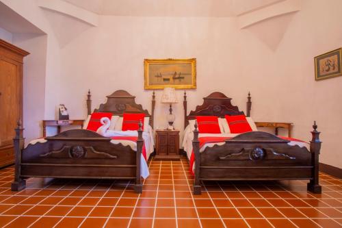 a bedroom with two beds with red pillows at Hotel Posada de Don Rodrigo Antigua in Antigua Guatemala