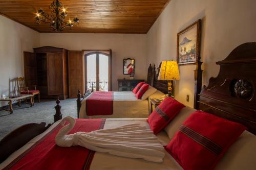 a bedroom with two beds and a couch and a chandelier at Hotel Posada de Don Rodrigo Antigua in Antigua Guatemala