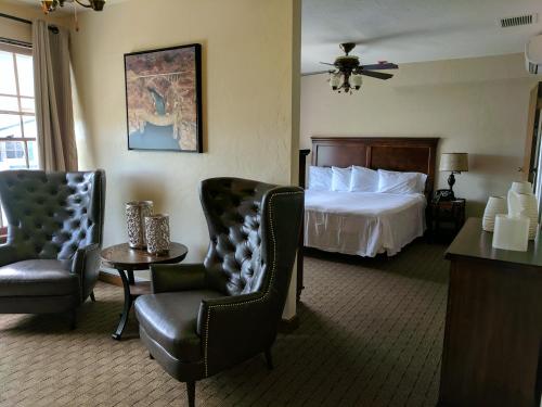 a hotel room with a bed and two chairs at Boulder Dam Hotel in Boulder City