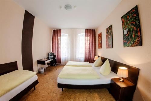 a hotel room with two beds and a desk at Hotel-Pension Victoria in Berlin