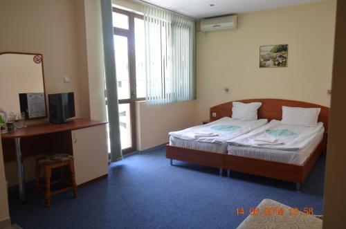 a bedroom with a bed and a desk and a television at Guesthouse Opal in Ravda