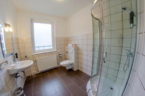 a bathroom with a shower and a toilet and a sink at Hotel-Pension Victoria in Berlin