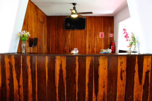 a wooden bar in a room with a ceiling fan at Hotel Berny in Isla Mujeres