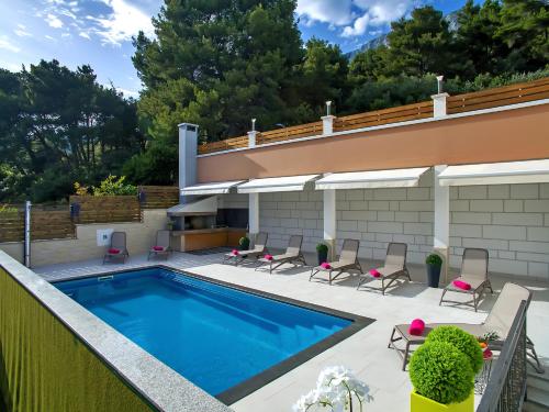 a swimming pool with chairs and a house at Apartments Villa Katija in Drvenik
