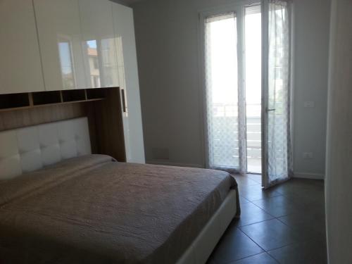 a bedroom with a bed and a large window at NUOVO BILOCALE IN VIA LAGOMAGGIO, 31 in Rimini