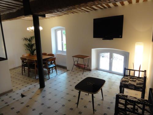 un salon avec une table et une télévision au mur dans l'établissement La Maison des Augustines, à Marseille