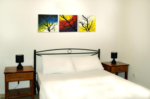 a bedroom with three paintings on the wall at Sky-Line Apartments in Afantou