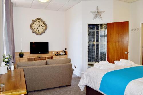 a living room with a couch and a clock on the wall at Avenue Guest House in Blackpool