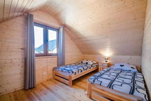 two beds in a wooden room with a window at Na Slonecznym Wzgorzu in Władysławowo