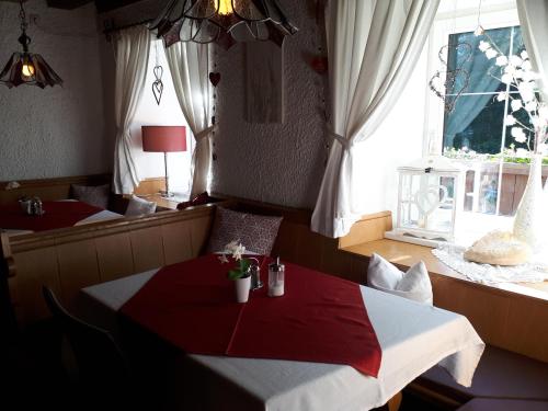 une salle à manger avec une table rouge et blanche et une fenêtre dans l'établissement Gasthaus Vinaders, à Gries am Brenner