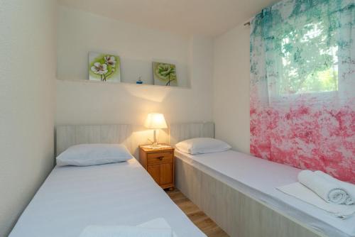 two twin beds in a room with a window at Apartment PAULA in Trogir
