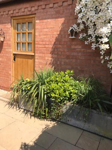 a brick building with a door and some plants at The Burrow in Wellesbourne Hastings