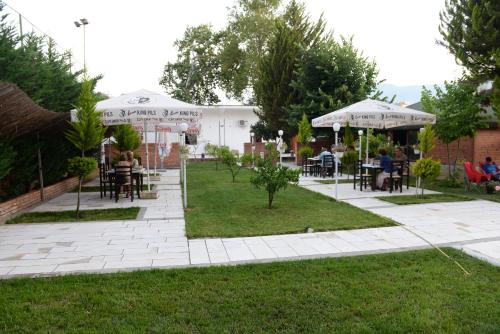 a patio with people sitting at tables and umbrellas at Villa Juri Garden in Berat