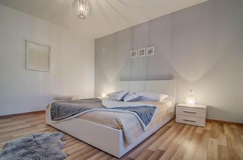 een witte slaapkamer met een bed en een nachtkastje bij Apartments Prodan in Fažana