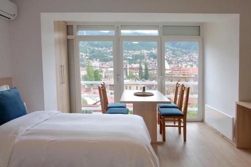 萨拉热窝Deluxe Bellevue Apartments的一间卧室，里面有一张床、一张桌子和几把椅子。