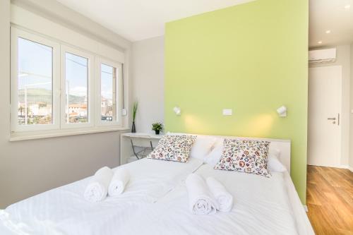 a bedroom with a white bed with two pillows at 4 Elements Old Town Views Rooms in Trogir