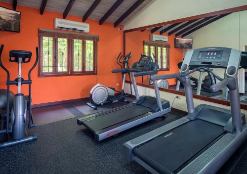 a gym with two tread machines and orange walls at Sugar Cane Club Hotel & Spa in Saint Peter