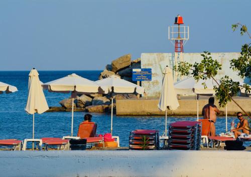 a group of people sitting on a beach with chairs and umbrellas at Venetia in Tsoútsouros