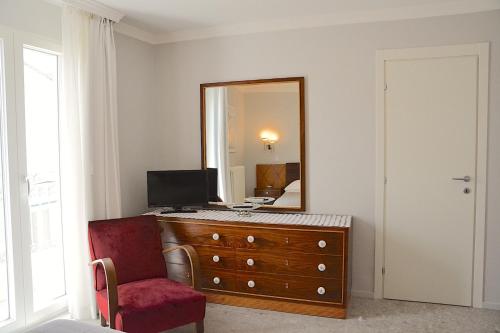 a bedroom with a dresser with a mirror and a red chair at Vacanze Murgiane in Altamura