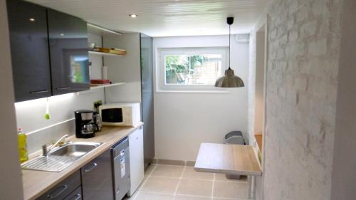 Elle comprend une petite cuisine avec un évier et une fenêtre. dans l'établissement Appartement les Acacias, à Clamart