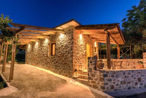 una casa de piedra con luces encendidas por la noche en Krassopsychia Apartments, en Krásion