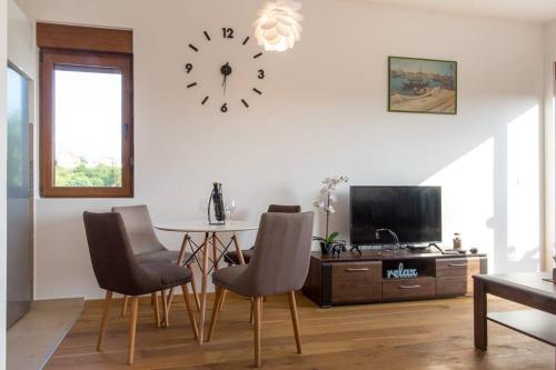 a living room with a table and a clock on the wall at Porto Apartments in Tivat