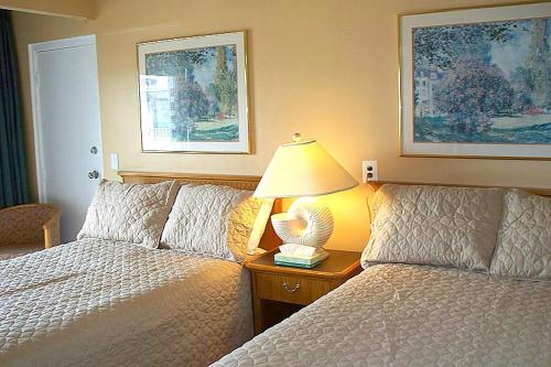 Aztec Ocean Resort في سيسايد هايتس: غرفة نوم بسريرين ومصباح على موقف ليلي