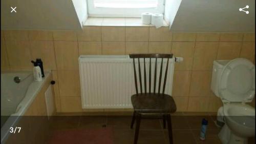 La salle de bains est pourvue d'une chaise, de toilettes et d'une fenêtre. dans l'établissement Mansarda, à Mýto pod Ďumbierom